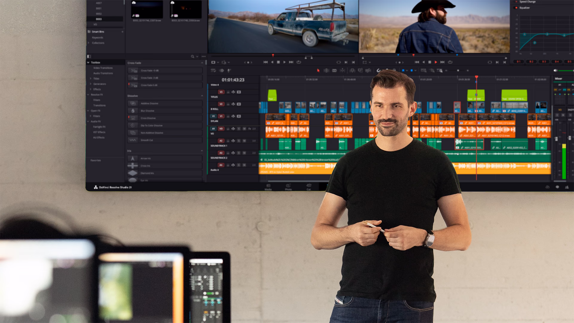 Kevin Blanc vor der Videowand im Schulungsraum, darauf eine DaVinci-Resolve-Zeitleiste
