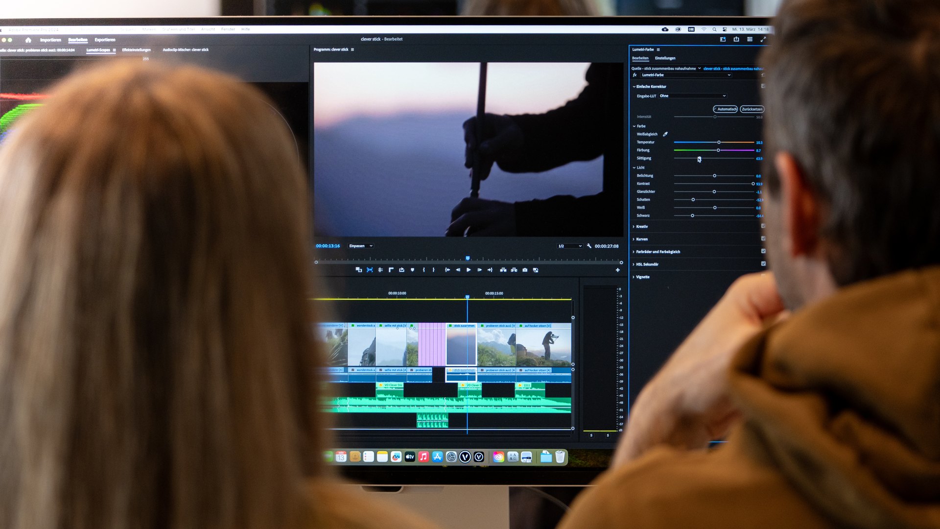Zwei Kursteilnehmende vor einem Bildschirm mit einer Premiere-Zeitleiste und dem Lumetri-Farbpanel