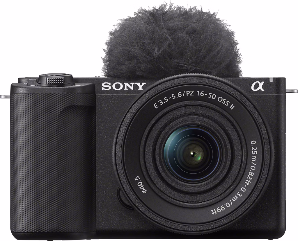Schwarze Sony Alpha Einsteiger Kamera 2026, großes Objektiv, unscharfer Mikrofon-Windschutz und strukturierter Griff auf der linken Seite, Vorderansicht.