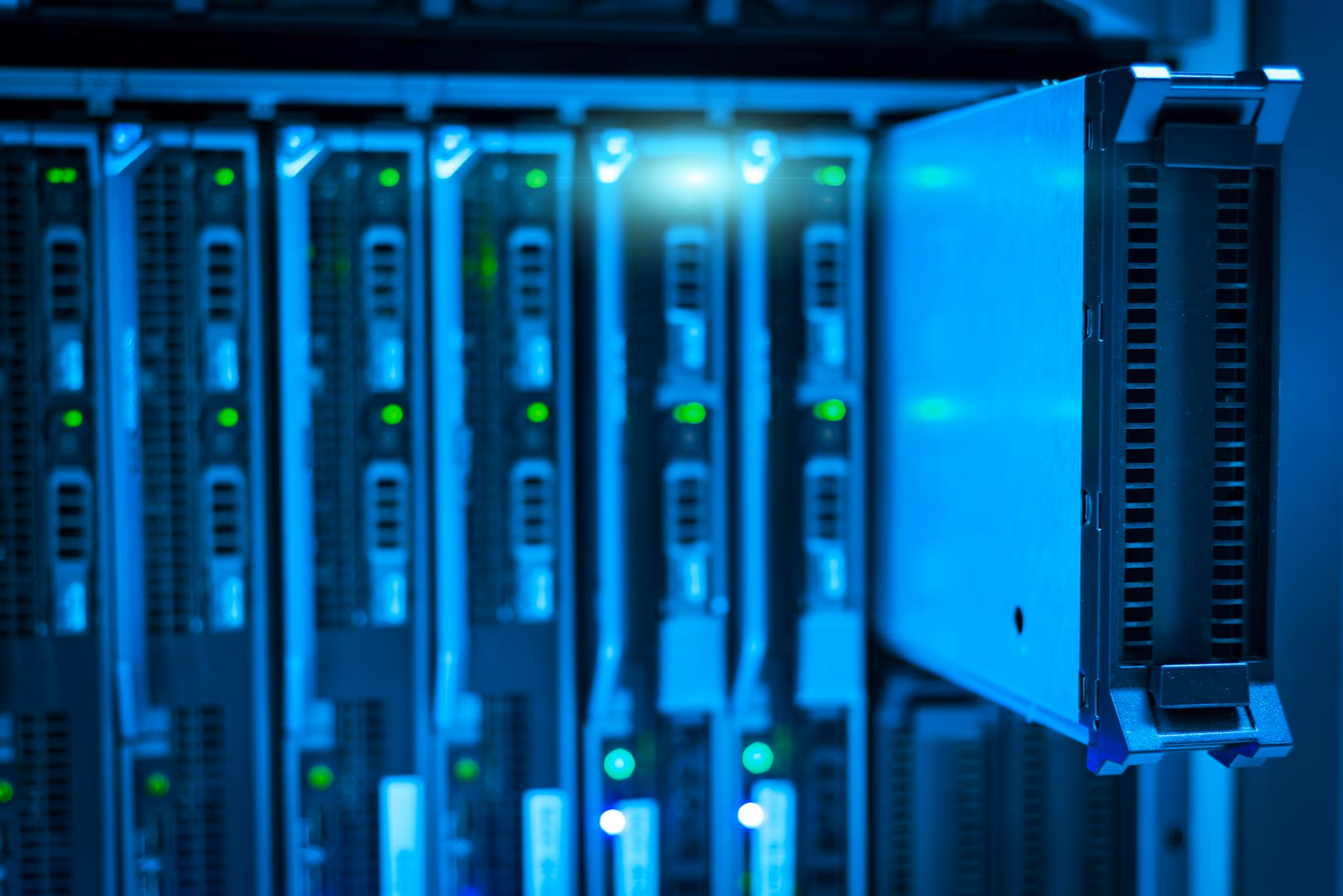 Mehrere dunkelgraue Serverracks in Reihe mit leuchtenden grünen und blauen Status-LEDs, rechts ein hellblaues Gehäuse mit Kühlrippen