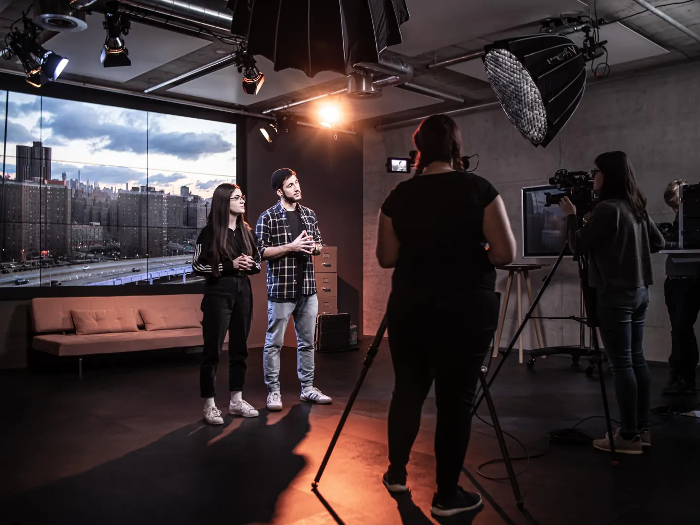Auftrittskompetenz-Training im Videostudio von Studio 1 in Wallisellen: zwei Personen vor laufender Kamera in Gesprächsposition, professionelle Beleuchtung, Kameramann und Crew sichtbar.