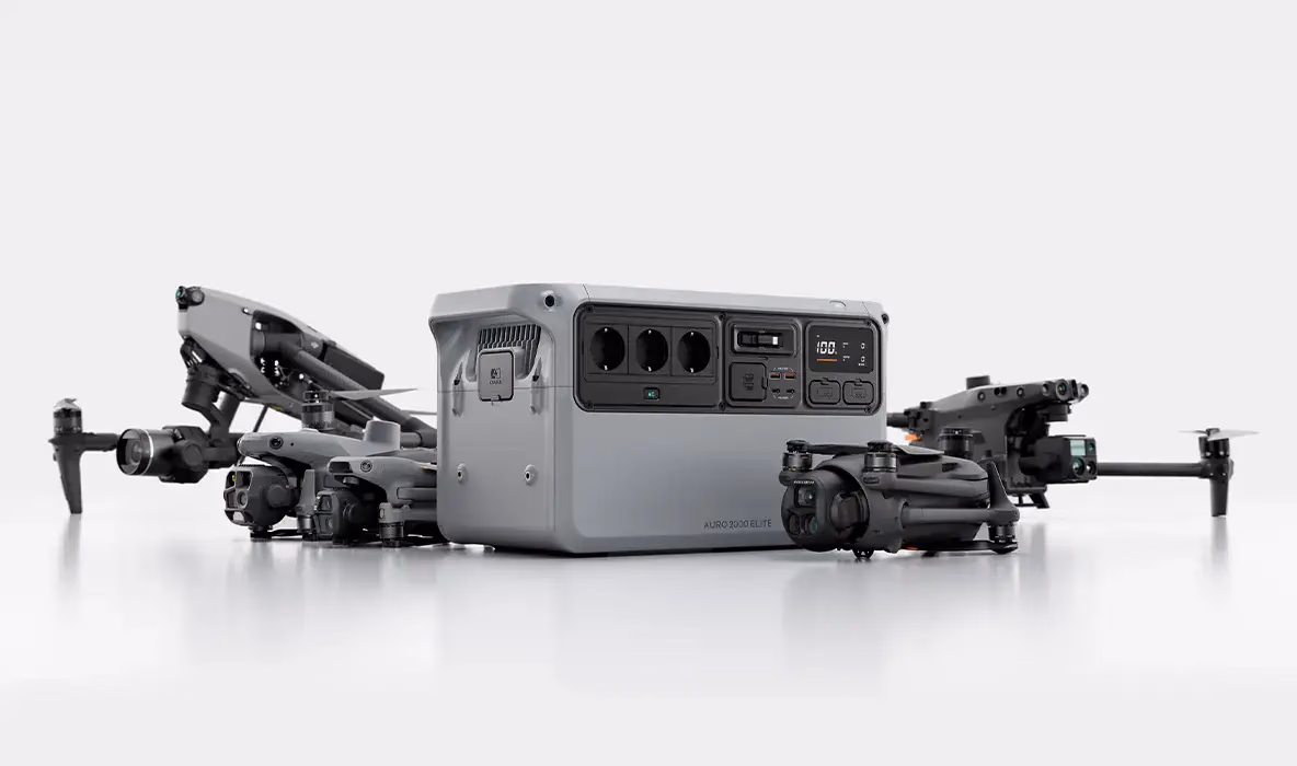 Graue DJI-Drohnen liegen neben einer tragbaren Powerstation mit drei Steckdosen, Display und Anschlüssen. Auf dem Gerät steht «POWER 2000 ELITE».